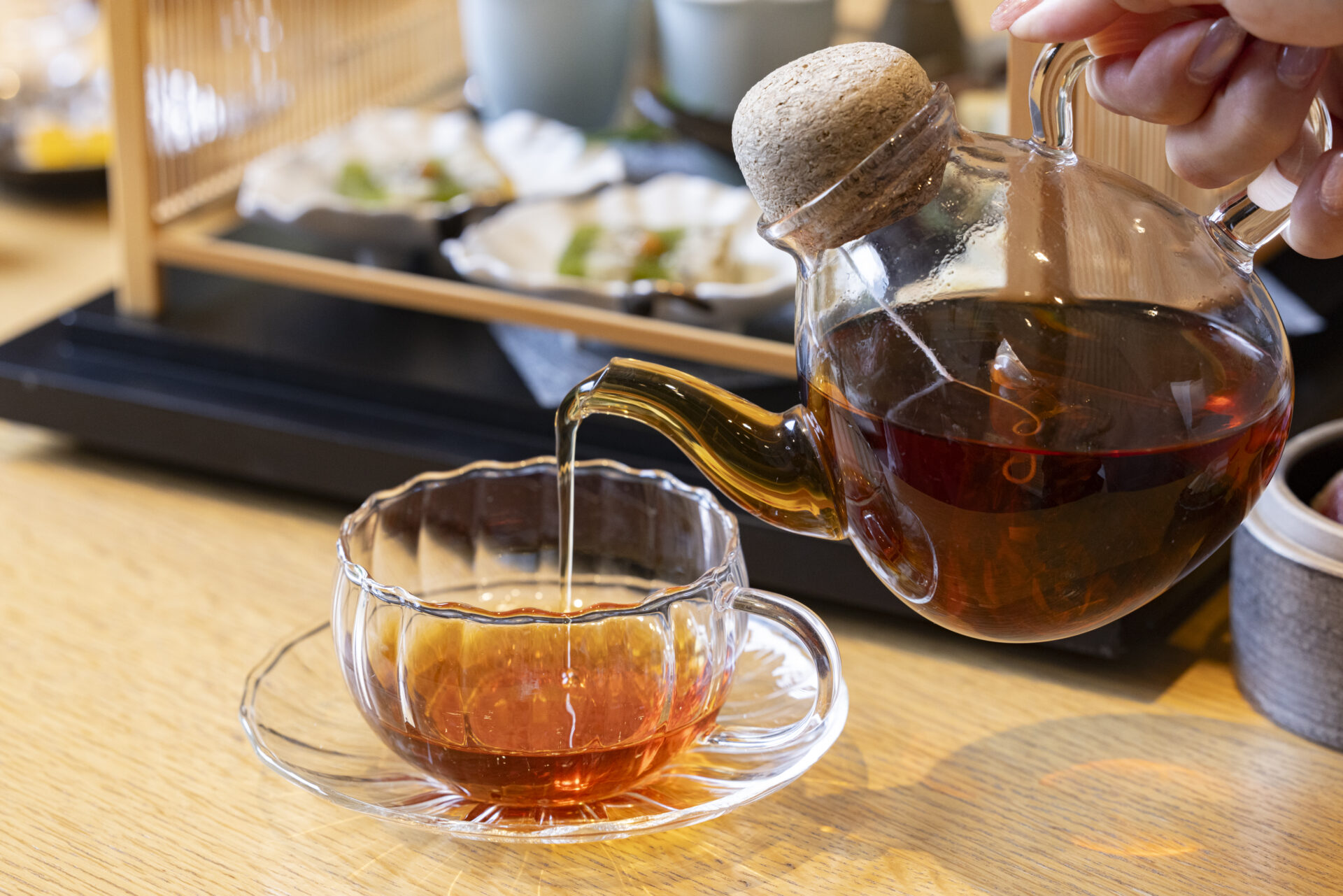 ティーポットからカップに紅茶を注いでいる様子